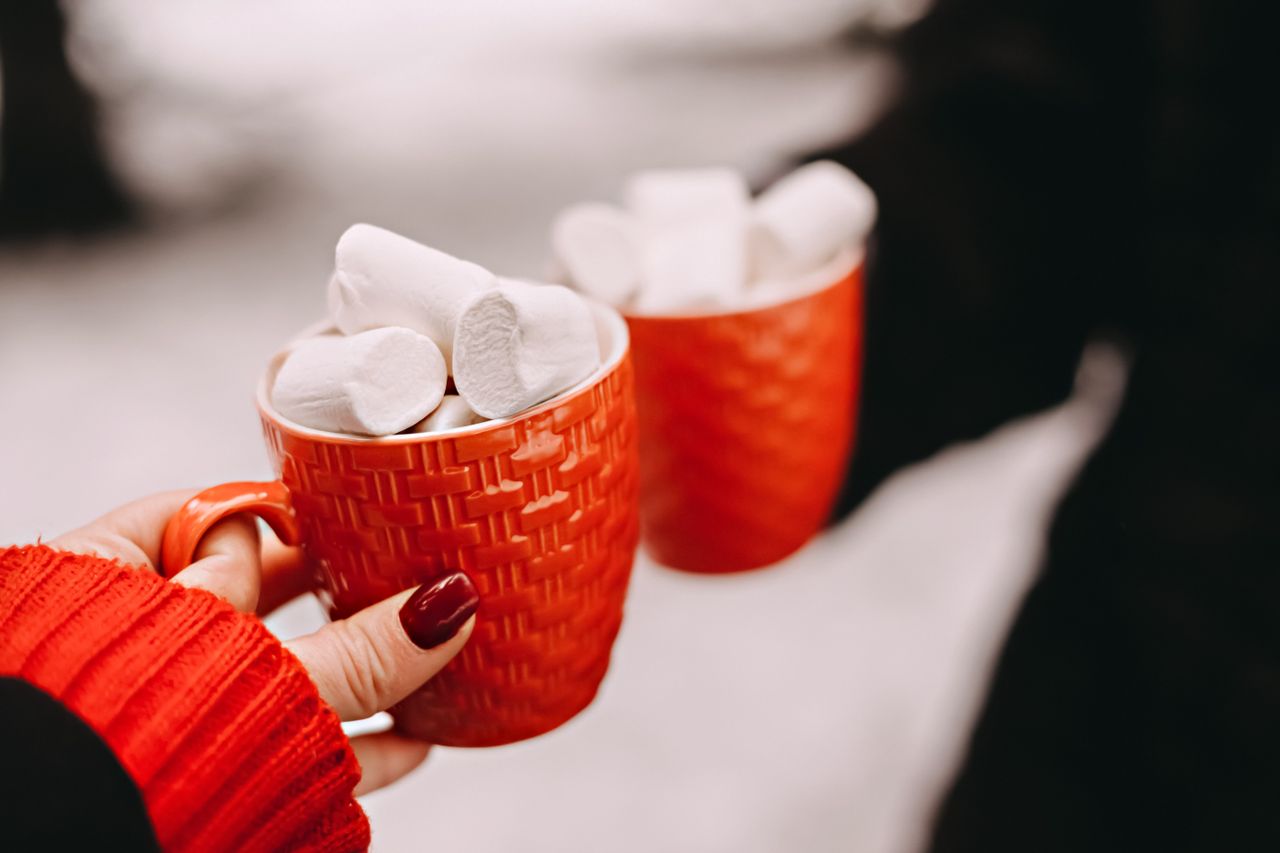 Cozy hot drink with marshmallows in red mugs, perfect for winter warmth and festive celebrations.