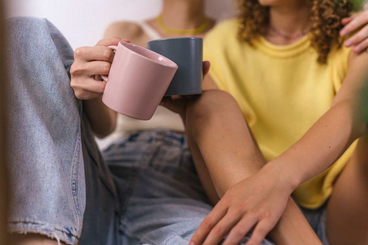 Close-up of a couple holding mugs, sharing a warm moment indoors.